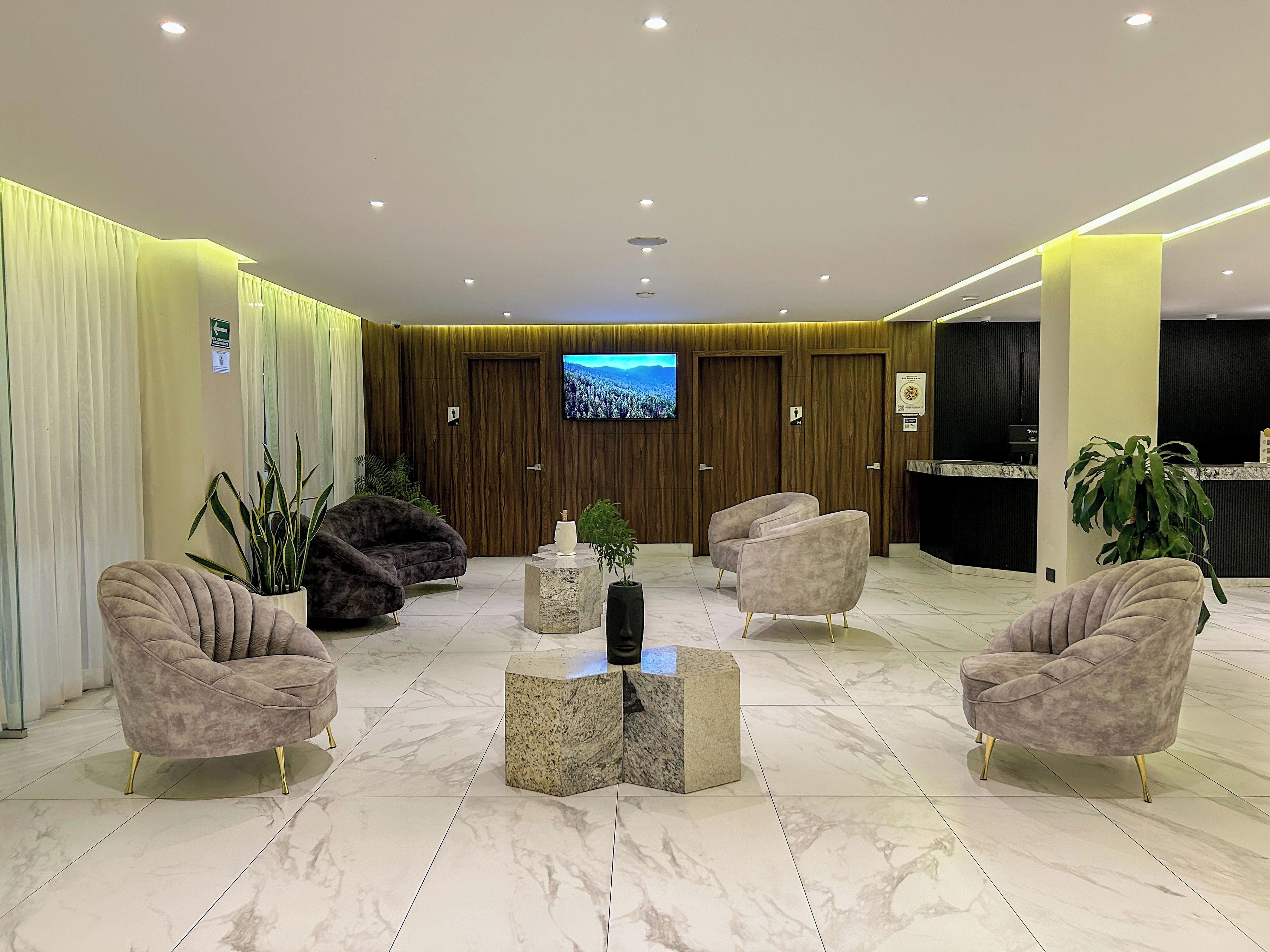 Een moderne lobby met marmeren vloer, comfortabele zithoeken, een centrale salontafel en een televisie aan de muur.