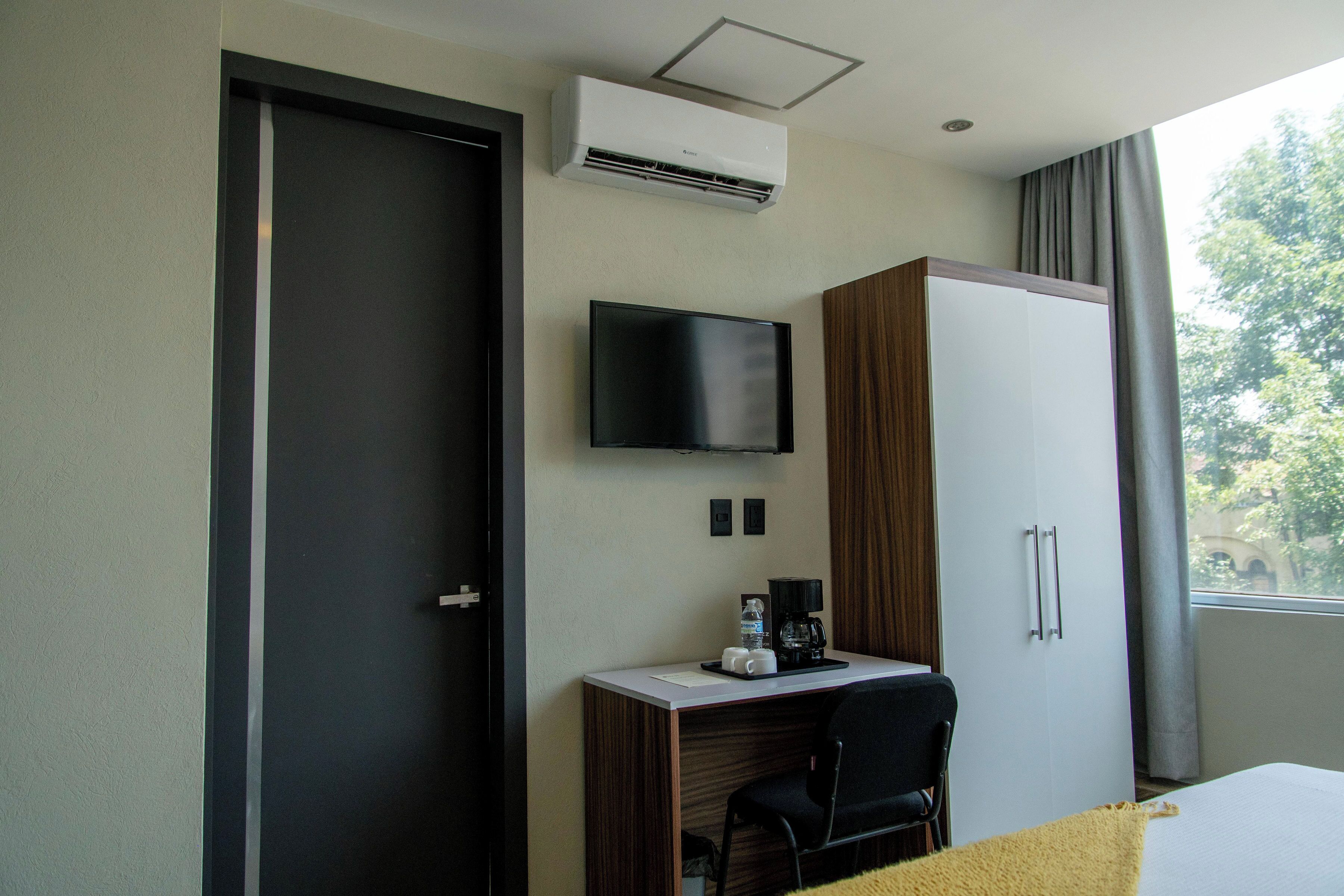 Une chambre d’hôtel équipée d’un bureau, d’une chaise, d’une télévision, d’une armoire et d’un appareil de climatisation.