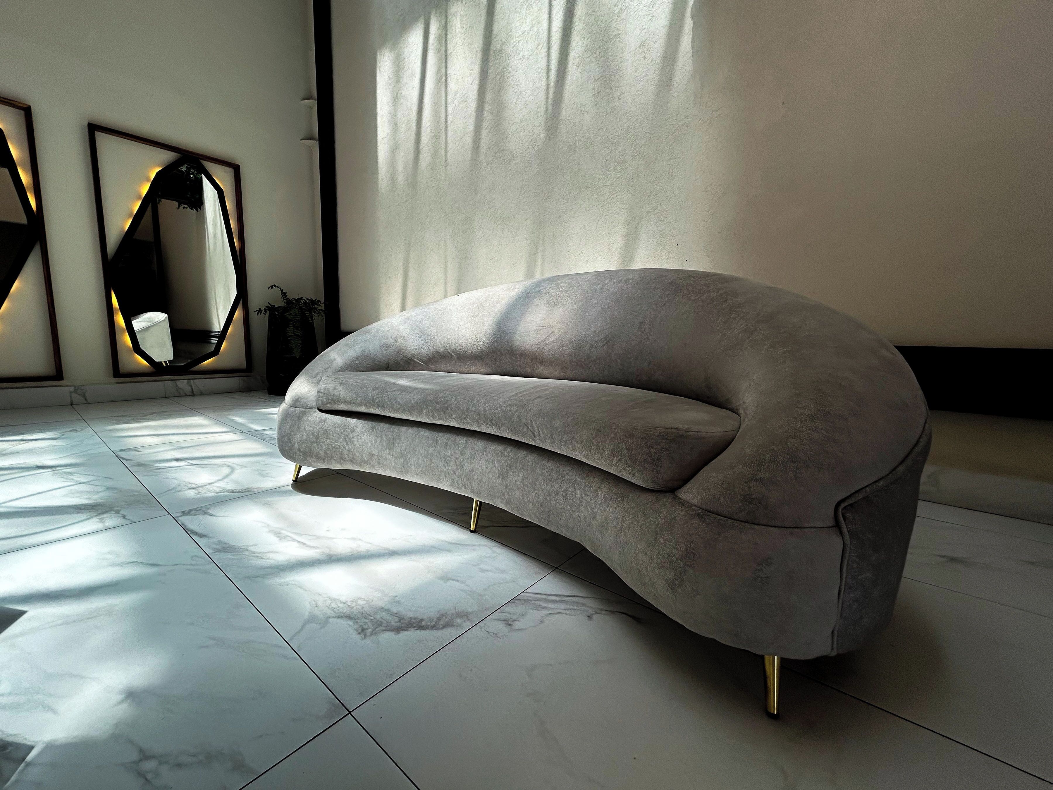 Un salon moderne avec un canapé gris, un grand miroir et un sol en marbre.