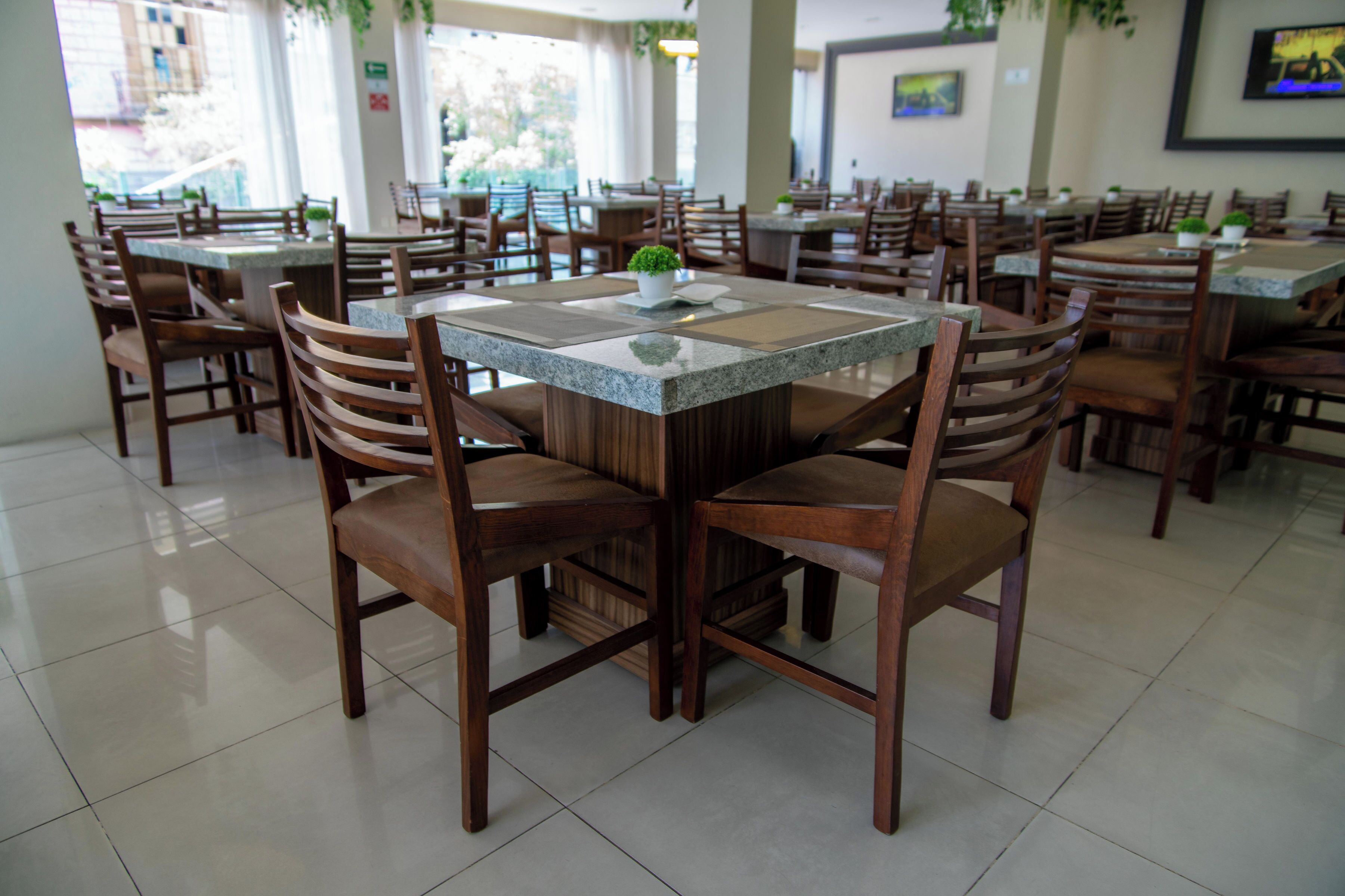A restaurant with wooden chairs and tables, some with potted plants.
