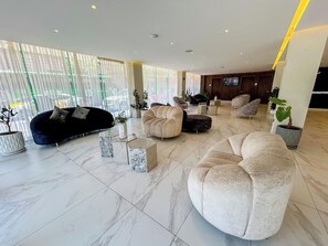 A spacious lobby with a black sofa, beige armchairs, and a marble-tiled floor. - HVH by Yaxché (Guadalajara)