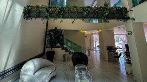 A spacious lobby with a high ceiling, skylight, and modern lighting fixtures. - HVH by Yaxché (Guadalajara)