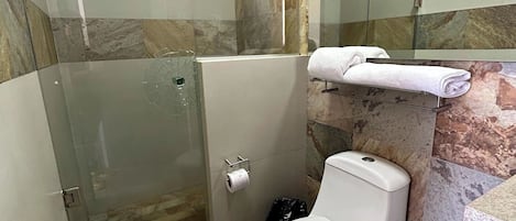 A bathroom with a glass shower enclosure, a toilet, and a towel rack.