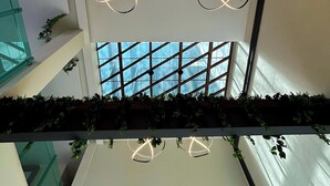A modern interior with a glass staircase, a geometric light fixture, and a view through a large window. - HVH by Yaxché (Guadalajara)