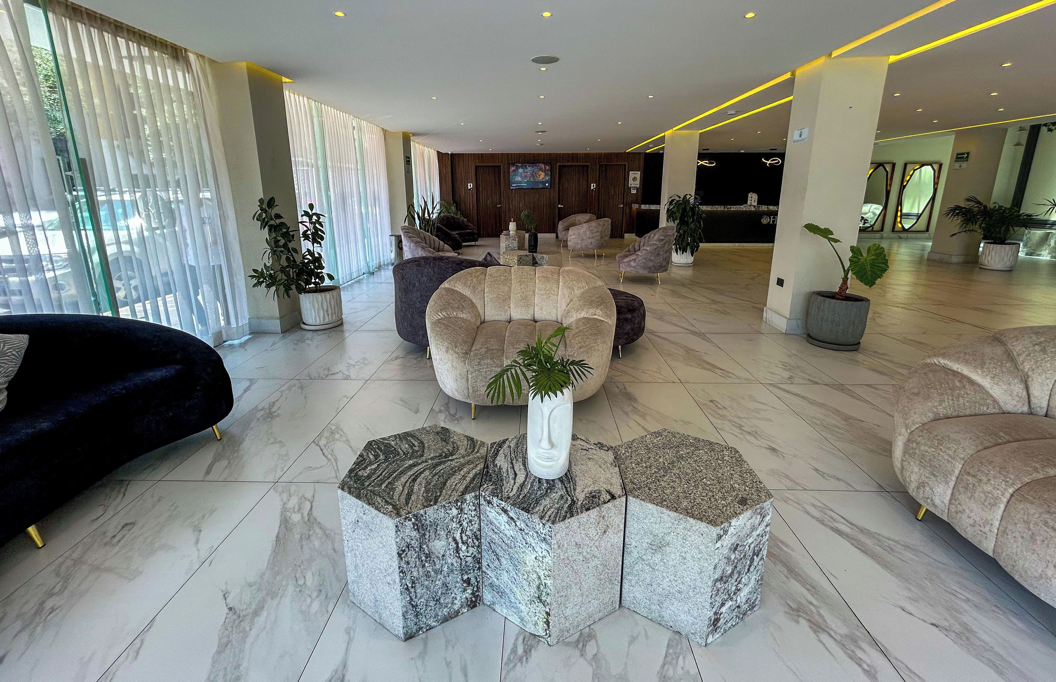 A modern lobby with a marble floor, seating areas, and potted plants.