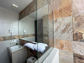 A modern bathroom with a glass shower enclosure, a built-in sink, and a towel rack. - HVH by Yaxché (Guadalajara)