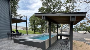 Ein überdachter Pool im Freien mit Stufen, umgeben von einer Terrasse und Gartenmöbeln.