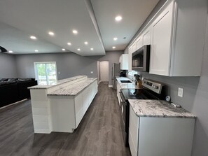 A modern kitchen with white cabinetry, a marble countertop, and a built-in oven. - 3 bedroom house w/plunge pool. Walking distance to Shady Gators and Horny Toad (Lake Ozark)