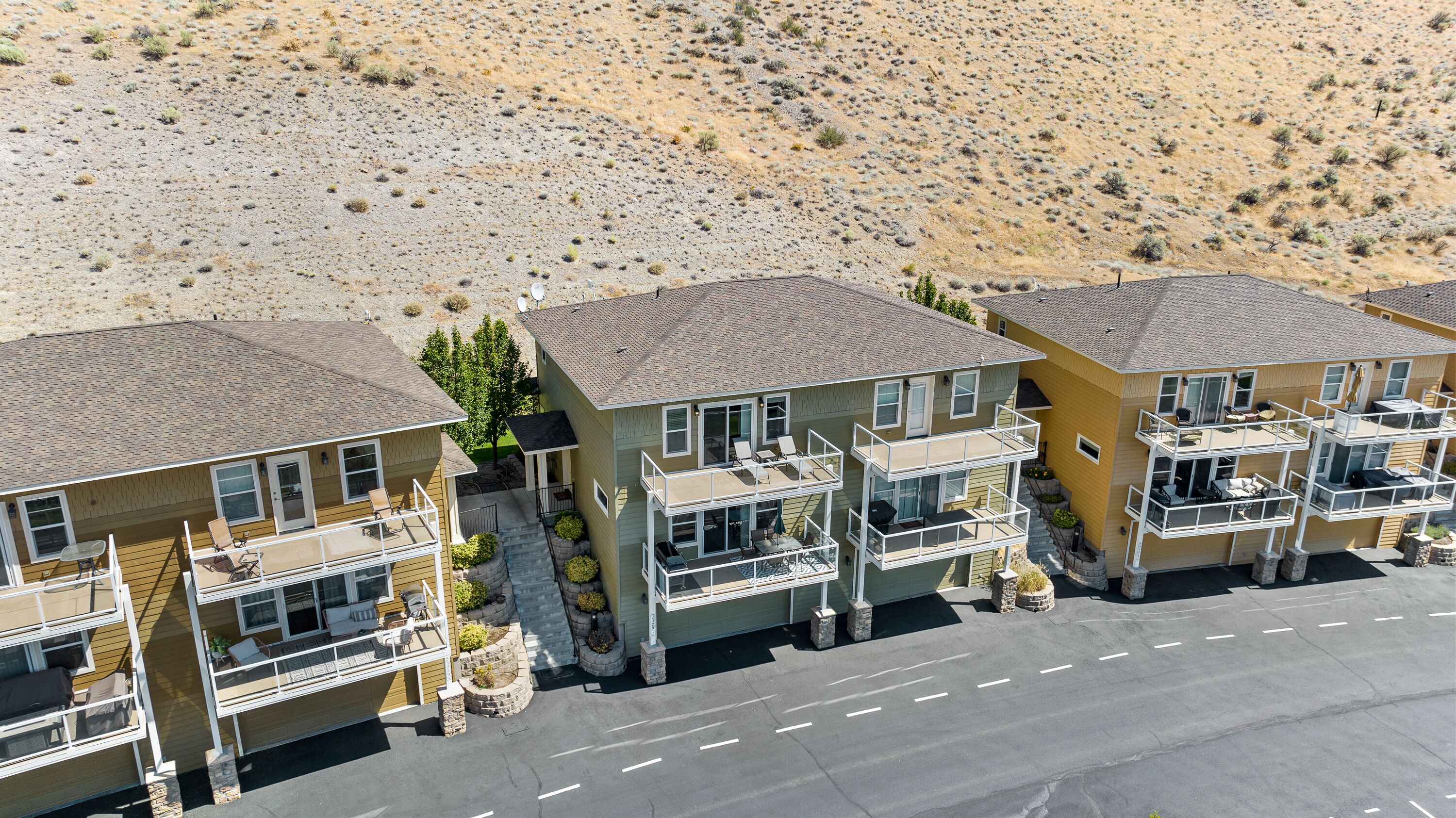 A row of two-story buildings with balconies, a paved road in front, and a desert landscape in the background.