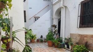 A paved courtyard with potted plants and a white building with a window and a door. - 113 Livingtarifa Amapola (Tarifa)