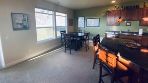 A kitchen with a dining area, large windows, and a bar area.
