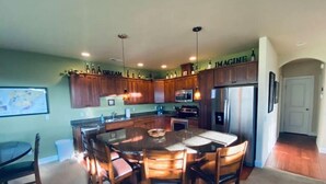 A spacious kitchen with wooden cabinets, a central island with chairs, a refrigerator, and a microwave.