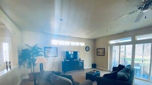 A living room with a sofa, a coffee table, a TV, and a plant.