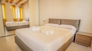 A hotel room with a large bed, a nightstand, a mirror, and a window with curtains.