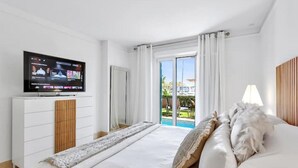 Una camera d'albergo con un letto, una televisione su un comò e vista sull'esterno tramite una porta scorrevole in vetro.
