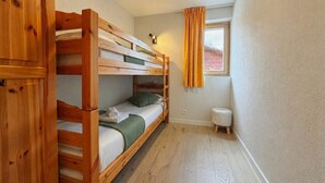 A small, compact room with a bunk bed and a single bed, wooden flooring, a small stool, and a window with curtains. - Pracondu 2 203 - OUTDOOR & FUN apartment 5 pers (Haute-Nendaz)