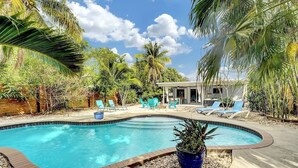 Una piscina rodeada de palmeras y sillas de descanso.