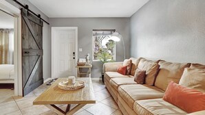 Un salón con un sofá color beige, una mesa de centro de madera y una puerta corredera tipo granero.