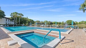 Ein rechteckiger Pool mit einem abgegrenzten flachen Bereich, umgeben von Liegestühlen und Sonnenschirmen.