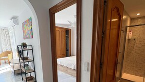A hallway with a wooden door, a mirror, and a tiled floor.