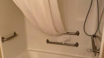A standard bathtub with a shower head, grab bars, and a towel rack.