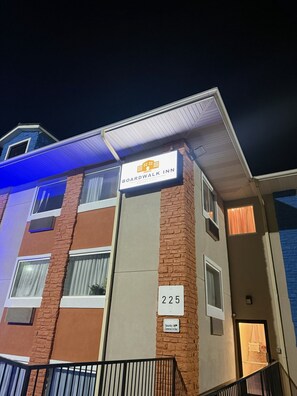 A multi-story building with a sign for Boardwalk Inn, featuring a brick facade, multiple windows, and a security camera warning. - The Boardwalk Inn (Branson)