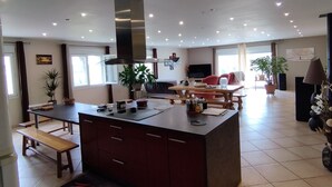 Una cocina amplia con una isla central, un rincón de comedor con un sofá rojo y un ventanal que proporciona luz natural.