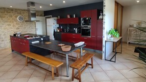 Una cocina moderna con una isla central, armarios rojos y una pared de acento de piedra.
