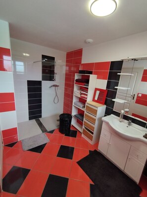 A bathroom with red and black tiles, a white sink, and a mirror.