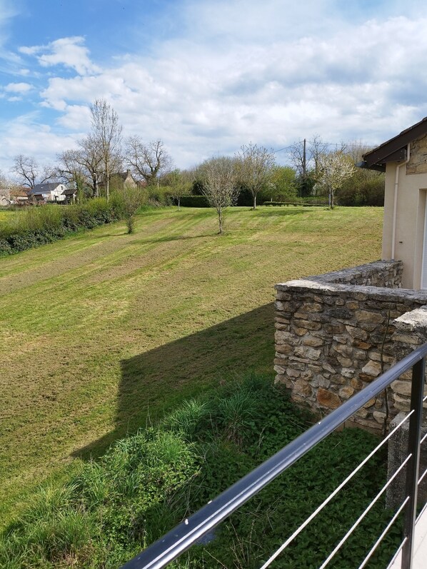 A view of a grassy field with a stone wall and a metal railing.