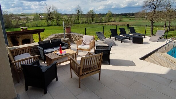 Un patio al aire libre con mobiliario, una parrilla y vistas al campo.