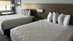 A hotel room with two beds, a desk, and a chair.