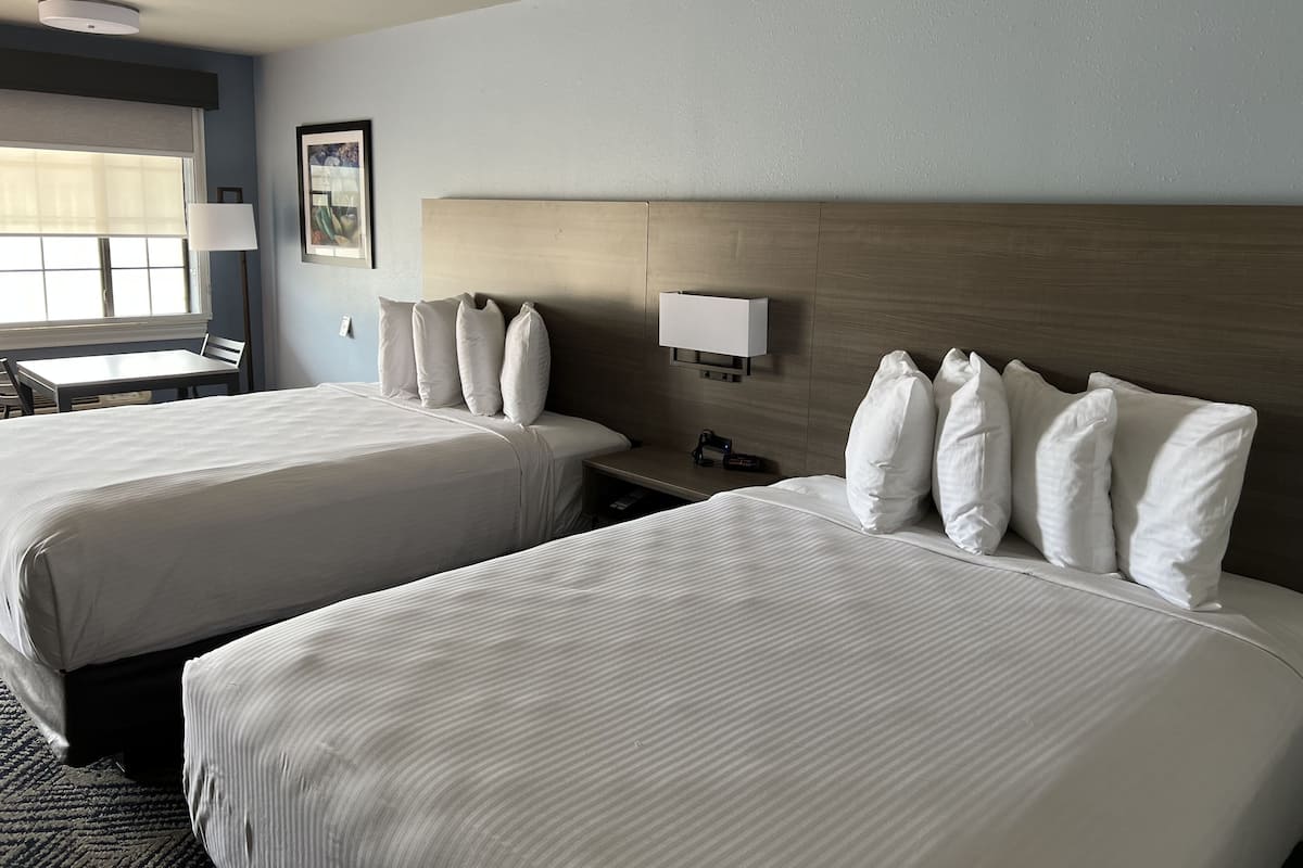 Ett hotellrum med två sängar, ett skrivbord och en stol.