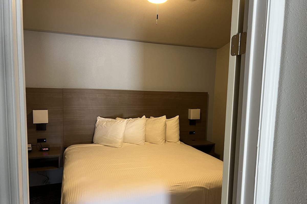 Ett hotellrum med en stor säng, två sängbord och ett litet bord vid sängen med en lampa.