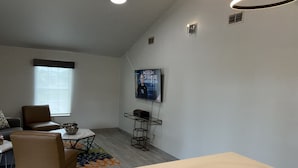A modern living room with a marble countertop, a television mounted on the wall, and a seating area with a patterned rug.
