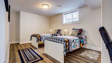 A bedroom with two beds, a window, a ceiling light, and a rug.