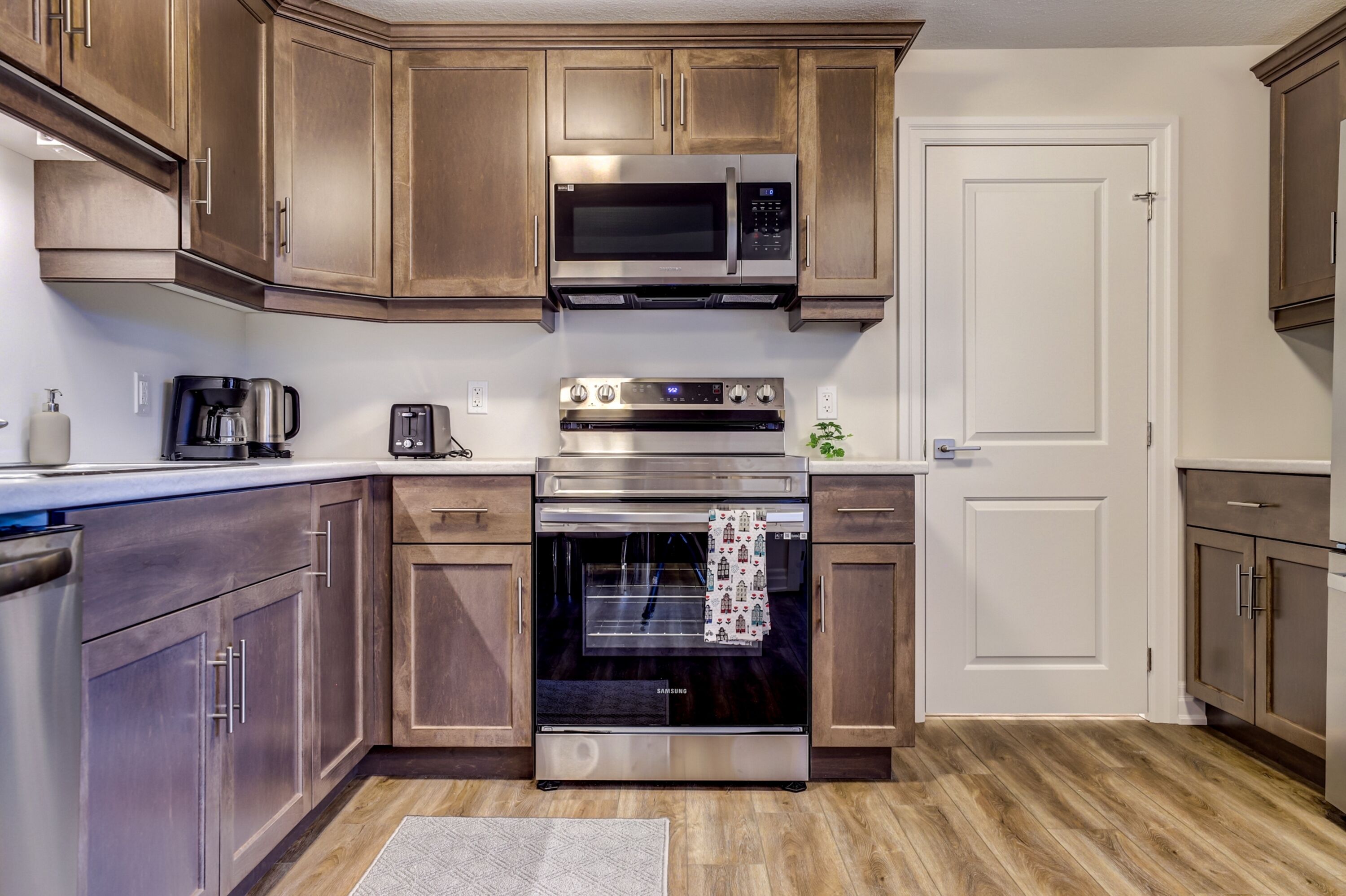 Una cocina con armarios de madera, un microondas de acero inoxidable, un tostador y un horno.
