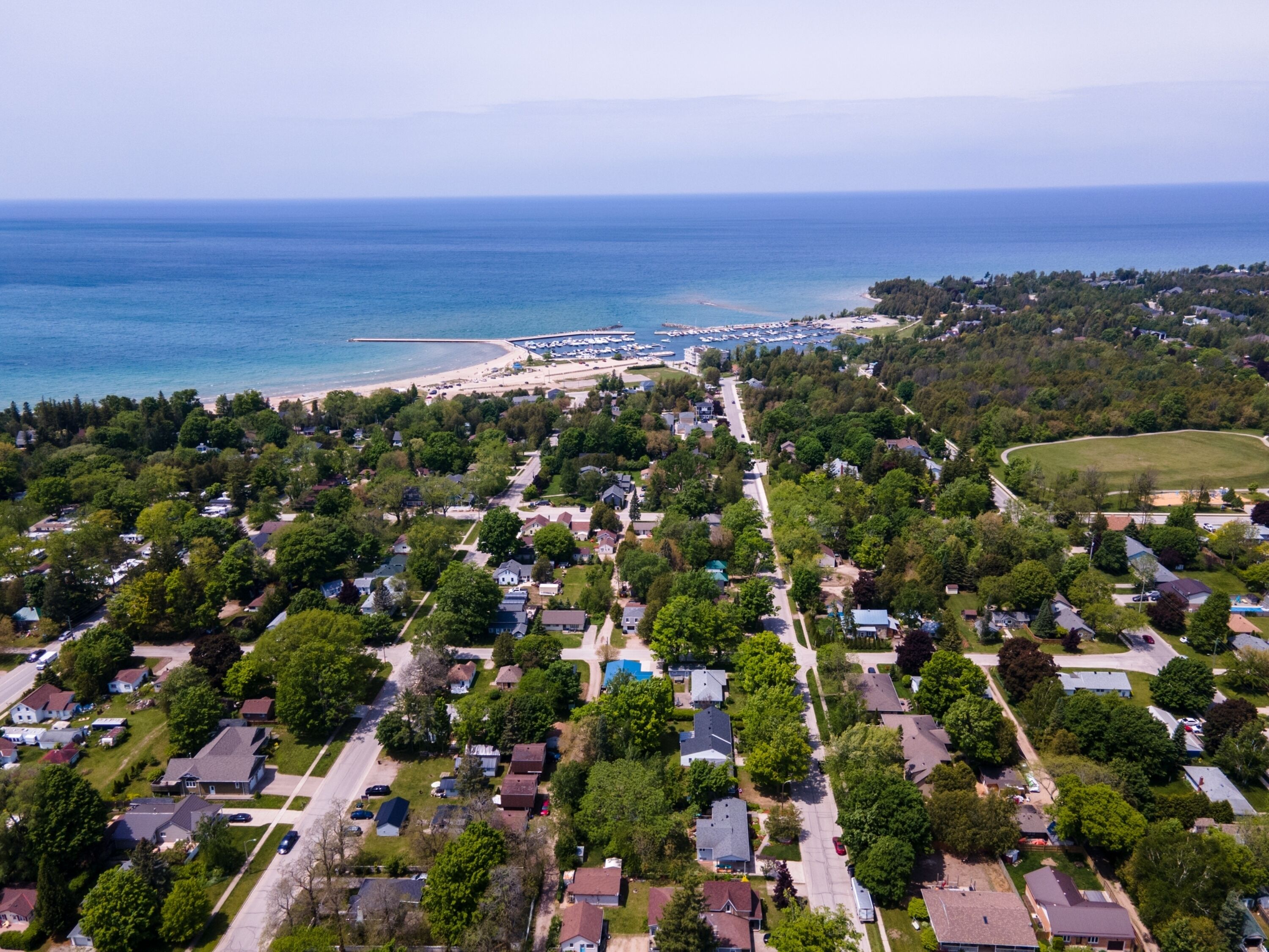 Vista aérea de una zona residencial costera con casas, una playa y un puerto deportivo.