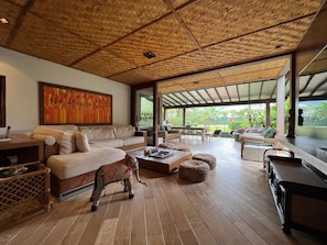 A spacious living area with a wooden ceiling, a large sofa, a coffee table, and a decorative elephant statue.