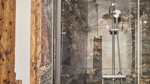 A modern shower with a glass enclosure, marble walls, and a wooden accent. - Meslay 1 - Three Bedroom Apartment, Sleeps 8 (Paris)