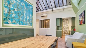 A modern interior with a wooden dining table, a sofa, and a colorful abstract painting. - Meslay 1 - Three Bedroom Apartment, Sleeps 8 (Paris)