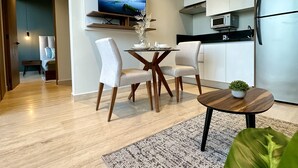 Une cuisine moderne équipée d’un four à micro-ondes encastré, d’un réfrigérateur en acier inoxydable et d’un coin repas avec une table et des chaises.