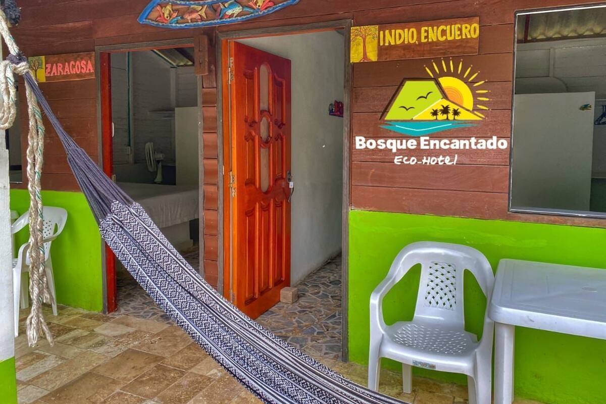 A hotel entrance with a hammock, a red door, and a sign reading "INDIO, ENCUERO".