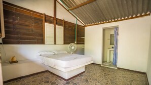 A bedroom with a stone-tiled floor, a bed with white bedding, a fan, and a wooden headboard. - Eco Hotel bosque encantado (Rosario Islands)