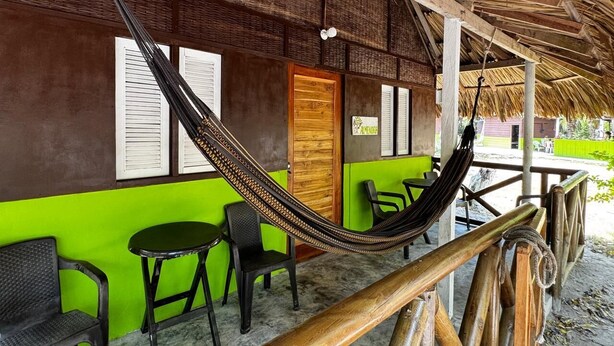 A hammock under a thatched roof, a wooden door, and a green wall with a window. - Eco Hotel bosque encantado (Rosario Islands)