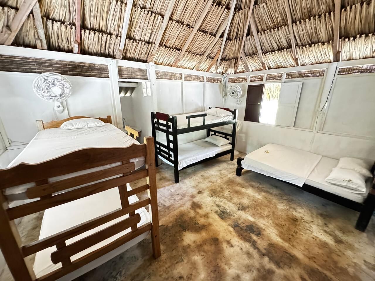 A room with bunk beds, a wooden chair, and a fan.