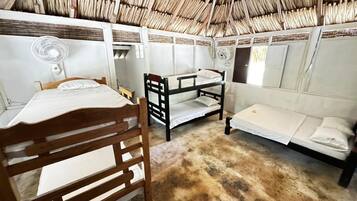 A room with bunk beds, a wooden chair, and a fan.
