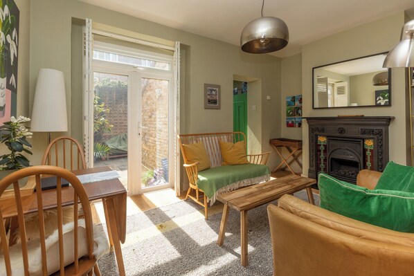 A cozy living room with a fireplace, a dining area with wooden furniture, and a view of the outside.