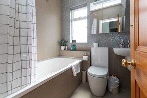 A modern bathroom with a bathtub, toilet, and sink.