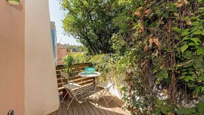A wooden deck with a table and chairs, surrounded by lush greenery and a wall. - Cosy 2 bed flat with terrace near Av Liberdade (Lisboa)
